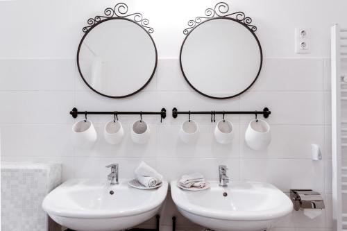 a bathroom with two sinks and two mirrors at OHANA Apartman Emelet - Kecskemét in Kecskemét