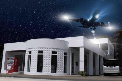 a plane is flying over a building with a car at Airport Terrace 1棟2階建貸切ヴィラ大型バルコニー サウナ 駐車場 ペット 屋内BBQ in Fukuoka