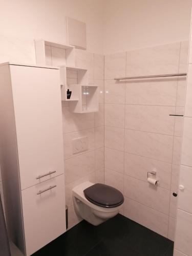 a white bathroom with a toilet with a black seat at 4 Ferienwohnung Franziska in Oberstaufen