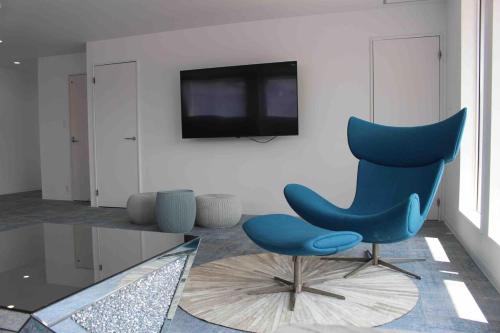 a living room with a blue chair and a tv at Airport Terrace 1棟2階建貸切ヴィラ大型バルコニー サウナ 駐車場 ペット 屋内BBQ in Fukuoka