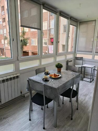 a table and chairs in a room with windows at APARTAMENTO DANAE centro ESS00359 in Zumaia