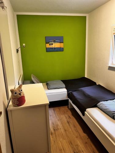 a room with two beds and a desk and green wall at Ferienwohnung Magdalena in Hohnstein