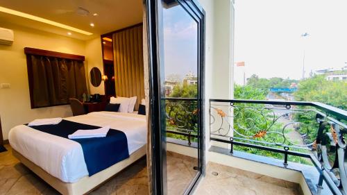 a hotel room with a bed and a balcony at The Velar Hotel, Vijay Nagar in Indore