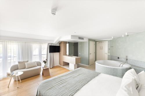a bedroom with a bed and a tub and a couch at Hotel Bommelje in Domburg