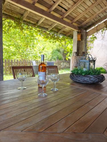 - une bouteille de vin et 2 verres à vin sur une table en bois dans l'établissement Gîte de Charme nature, calme, randonnée et air pur, à Le Valtin