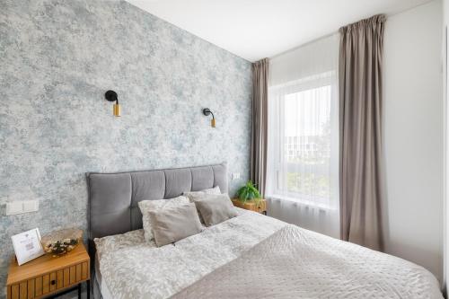 a bedroom with a bed with a gray wall at City Center Apartamentai Šatrijos g in Vilnius
