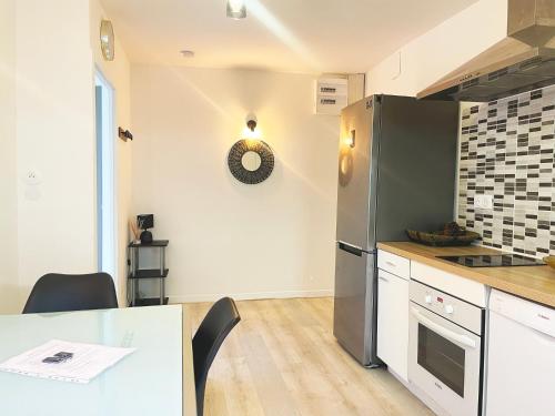 una cucina con frigorifero in acciaio inox e tavolo di Appartement pratique au centre-ville de Vesoul a Vesoul