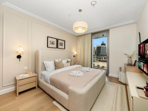 a white bedroom with a large bed and a window at The Dubai Mall Suite Luxury 1-Bed Near Burj Khalifa in Dubai