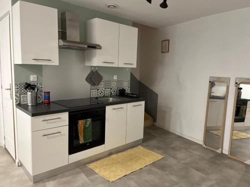 ロワイヤにあるMaison 4 personnes au centre de Royatのキッチン(白いキャビネット、黒いコンロ付)