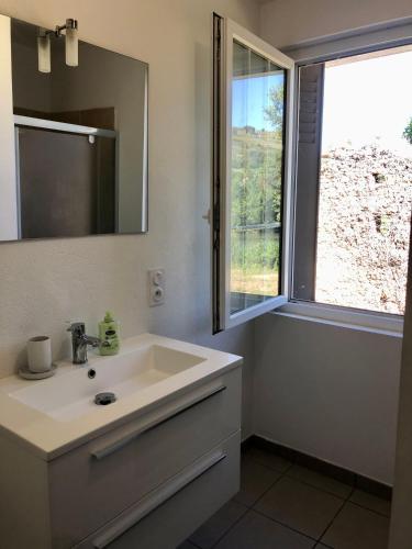 une salle de bain avec un lavabo, un miroir et une fenêtre dans l'établissement La Maison de l'Aqueduc, à Cournanel