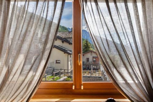 a window with curtains and a view of a town at La Vieille Cloche in Saint-Rhémy-en-bosses