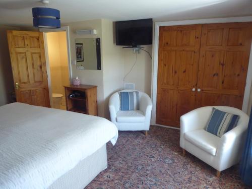 a bedroom with a bed and two chairs and a television at Yellow House in West Woodburn