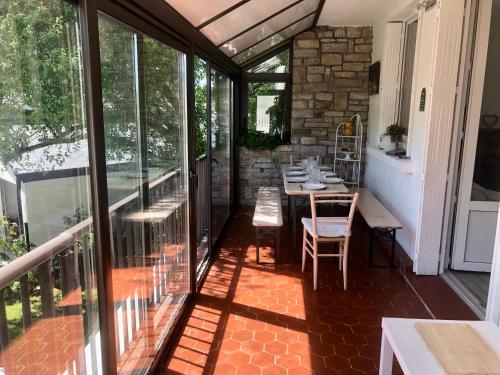une véranda avec une table et des chaises dans l'établissement Ty Kilek - entre bourg et plage, à Saint-Gildas-de-Rhuys