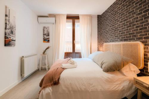 a bedroom with a large bed with a brick wall at Casa Augusta Renovada Centro Histórico 5 Pax in Zaragoza