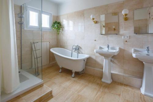 a bathroom with two sinks and a bath tub and a sink at Villa de la Cloche by Villa Plus in Pouzolles