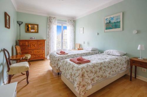 a bedroom with two beds and a table and a dresser at Villa de la Cloche by Villa Plus in Pouzolles