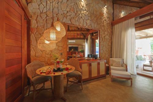a living room with a table and a stone wall at Anttunina Pousada e SPA in Maragogi