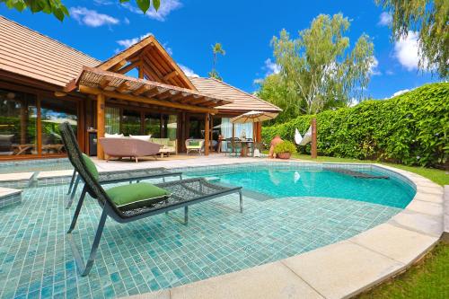 a swimming pool with a chair next to a house at Anttunina Pousada e SPA in Maragogi