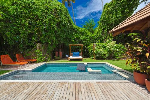 a swimming pool in a backyard with chairs and a table at Anttunina Pousada e SPA in Maragogi