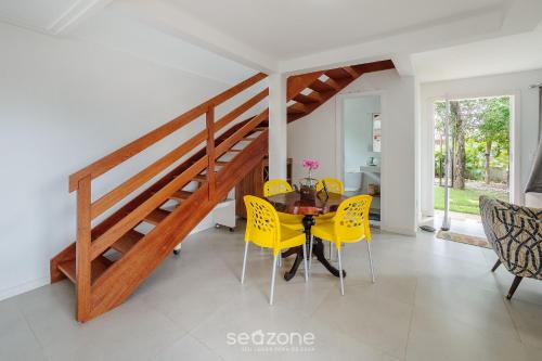 a dining room with a table and yellow chairs at Casa charmosa em Imbassaí c/ piscina | RTQ0009 in Imbassai