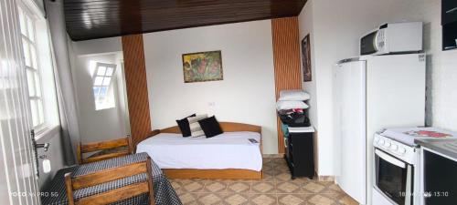 a small bedroom with a bed and a refrigerator at Vilarejo da Esperanza in Campos do Jordão