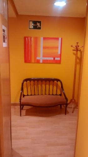a bench in a room with a yellow wall at Hostal Álvarez in Oviedo
