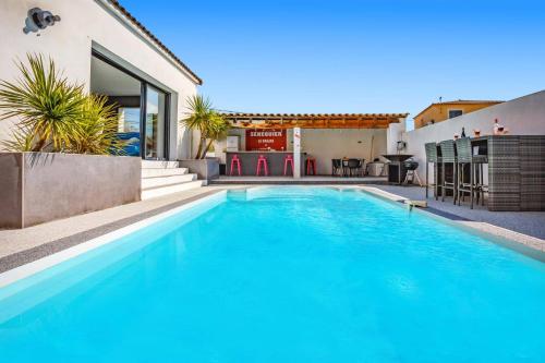 une grande piscine bleue à côté d'une maison dans l'établissement Villa Manade by Villa Plus, à Le Cailar