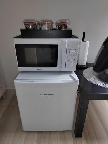 a microwave sitting on top of a white refrigerator at Séjour Détente près de Bayeux au Calme avec Massages et repas in Tilly-sur-Seulles