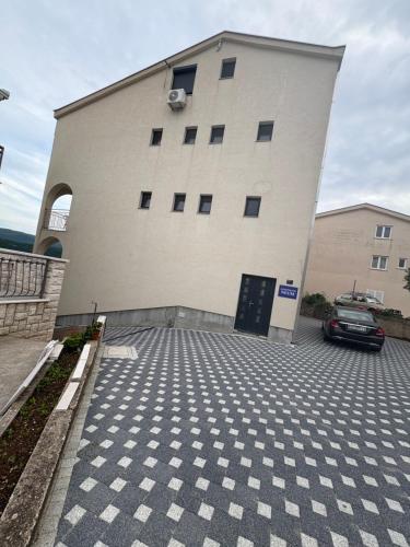a building with a car parked in a parking lot at Apartmani Neum in Neum