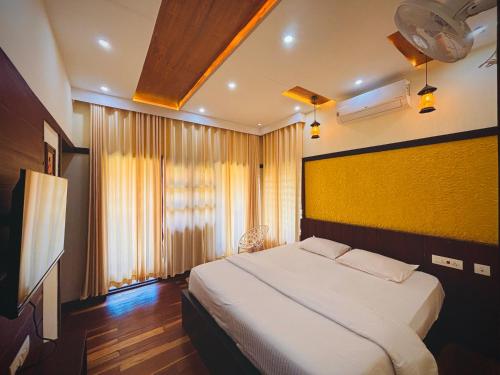 a bedroom with a large bed and a television at Vaca Vibes Resorts in Koroth