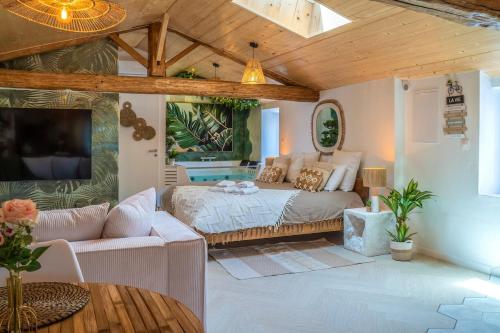 ein Schlafzimmer mit einem Bett und einer Couch in einem Zimmer in der Unterkunft Loft & Spa Scandinave Romantique, King Size, TV 65 in Narbonne