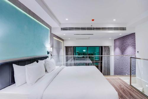 a bedroom with a large white bed and a balcony at Luxurious Residences by Sunday at M3M Broadway Sec 71 in Gurgaon