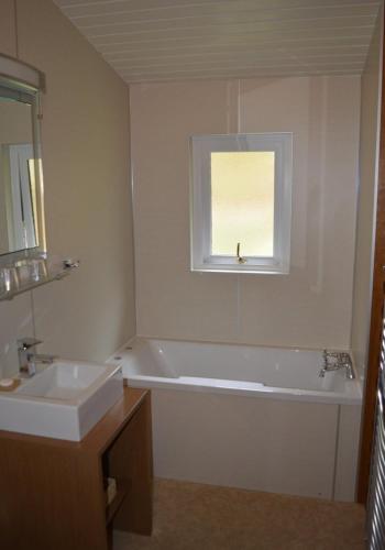 a bathroom with a tub and a sink and a window at Crowlin Lodge in Duirinish