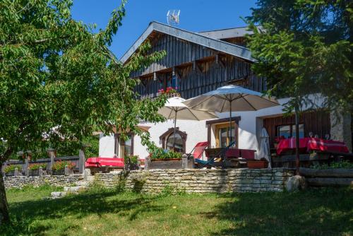 a house with chairs and umbrellas in front of it at Le chalet des Etoiles in Lavans-Vuillafans