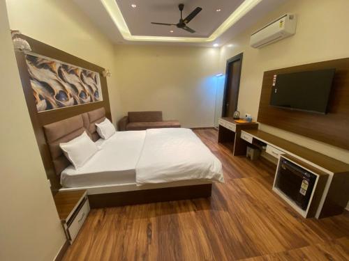 a bedroom with a bed and a flat screen tv at Pink Mahal Hotel & Resort in Jaipur