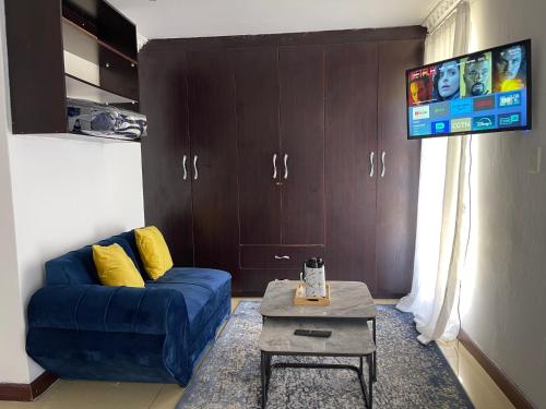 a living room with a blue couch and a tv at Homely Palace Guesthouse in Midrand