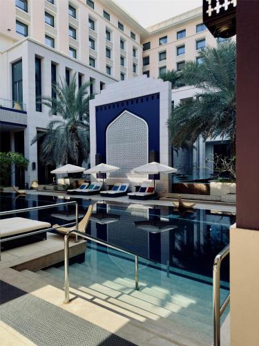 a hotel swimming pool with tables and umbrellas at Radisson Collection Muscat, Hormuz Grand in Muscat