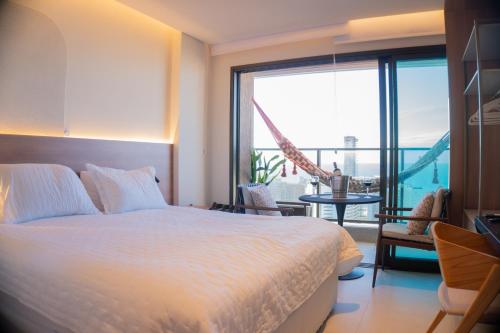 ein Schlafzimmer mit Bett und Balkon mit Aussicht in der Unterkunft Studio 25 andar a 350m da Beira Mar com Rooftop in Fortaleza