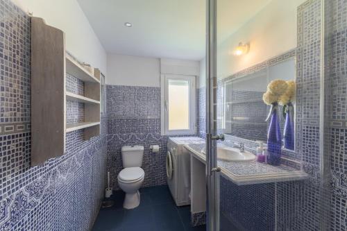 a blue tiled bathroom with a toilet and a sink at La Casa De Trasto in Ituero y Lama