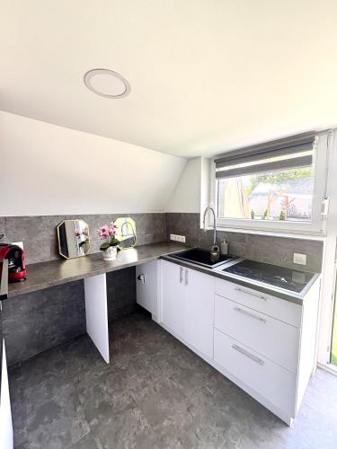 a kitchen with white cabinets and a sink and a window at PilisRelax-Stílusos Vendèghàz in Pilismarót