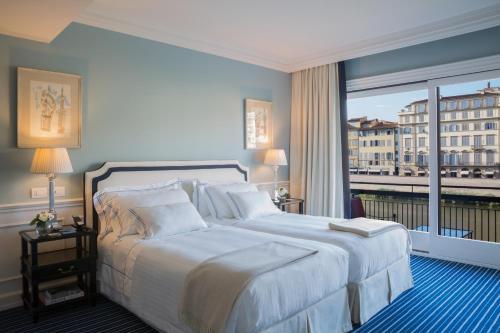 a bedroom with a large bed and a large window at Hotel Lungarno - Lungarno Collection in Florence