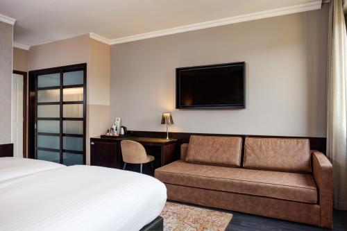 a hotel room with a bed and a couch and a television at Hotel Indigo Venice - Sant'Elena by IHG in Venice
