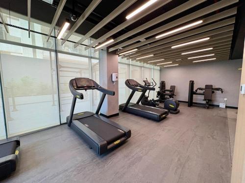 a gym with several treadmills and elliptical machines at Stylish Studio in JVC with Pool, Gym, Balcony & Modern Comforts in Dubai