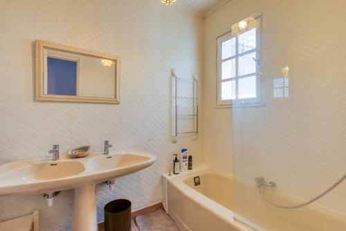 une salle de bain blanche avec un lavabo et une baignoire dans l'établissement Villa Montady avec piscine, à Montady