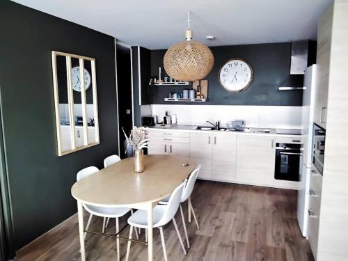une cuisine avec une table, des chaises et une horloge dans l'établissement Appartement 4 chambres et 4 salles de bains, à Reims