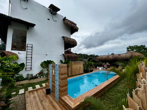 a villa with a swimming pool in front of a house at La Palapa Inn Port Barton in San Vicente