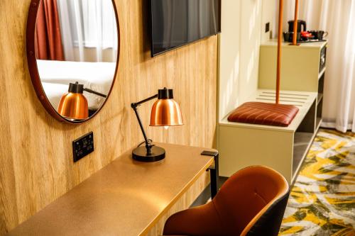 a room with a desk with a lamp and a mirror at ibis Styles York Centre in York