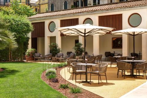an outdoor patio with tables and chairs and umbrellas at Hotel Indigo Venice - Sant'Elena by IHG in Venice