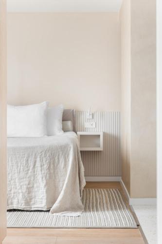 a white bedroom with a bed and a rug at Hotel Bommelje in Domburg