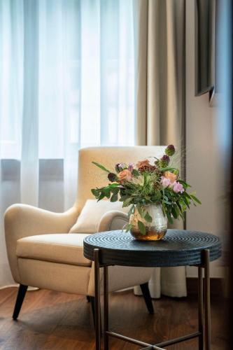 a living room with a couch and a vase of flowers on a table at Grand Hotel des Bains Kempinski in St. Moritz